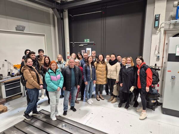 Sonniger Exkursionstag der Euro-Schulen Dresden: Spannende Einblicke in Wissenschaft und Kultur Eine weitere Gruppe von Besuchern posiert für ein Gruppenfoto in einem industriellen oder wissenschaftlichen Labor. Im Hintergrund sind Maschinen und technische Geräte zu sehen.