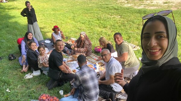 Ausflug zur Gedenkstätte Sachsenhausen Teilnehmende sitzen auf Decken zu einem kleinen Picknick auf einer Wiese beisammen.