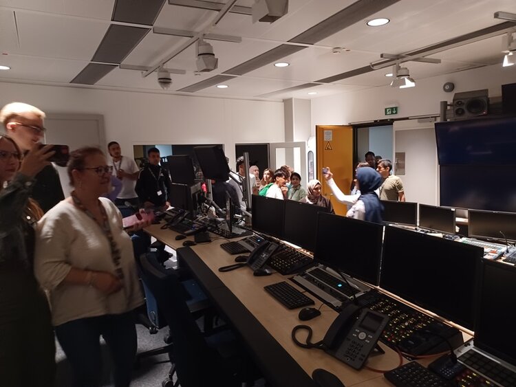 Berufssprachkurs besucht Fernsehsender Die Teilnehmenden der Euro-Schulen Mainz sehen sich im Aufnahmeraum des Fernsehstudios um, in dem viele Bildschirme und Computer sowie Telefone stehen.