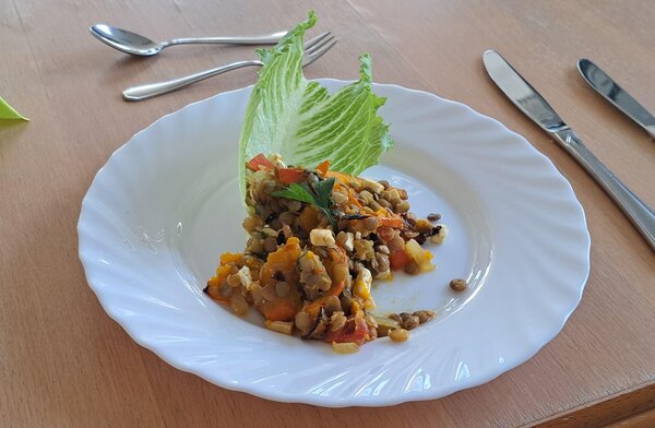 BRAFO-Projekt: Kreative Küche bringt Vielfalt auf den Tisch Auf einem Teller befindet sich ein kleiner Haufen von Linsen mit Gemüse, welches wie ein Eintopf aussieht.