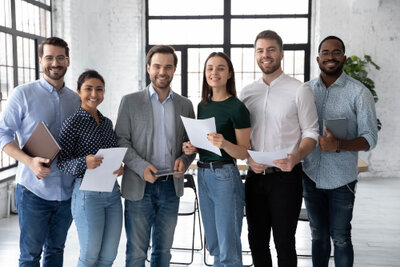 Gruppenbild junge Geschäftsleute Gruppenbild von lächelnden jungen, weiblichen und männlichen Geschäftsleuten unterschiedlicher Herkunft. Jeder hält etwas in der Hand, beispielsweise ein Tablet, einen Kaffeebecher und Papiere.