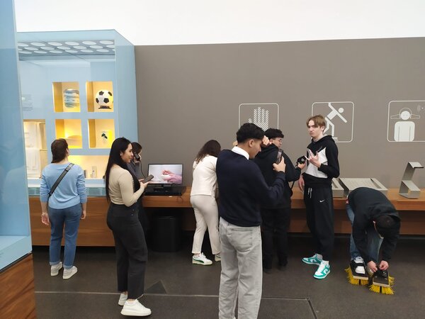 Sonniger Exkursionstag der Euro-Schulen Dresden: Spannende Einblicke in Wissenschaft und Kultur Eine Gruppe von Menschen erkundet eine Ausstellung mit interaktiven Elementen. Einige nehmen an Experimenten teil, während andere sich umschauen oder Fotos machen.