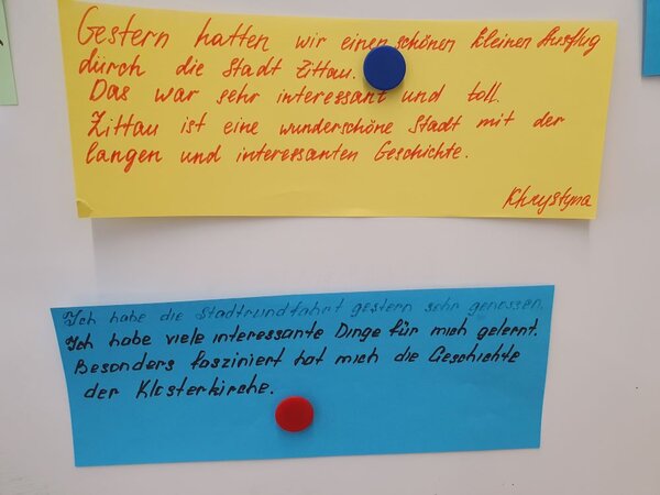 Auf den Spuren der Geschichte Zittaus Zwei handgeschriebene Feedback-Karten sind an einer Pinnwand befestigt. Die obere Karte auf gelbem Papier beschreibt eine positive Erfahrung in Zittau, während die untere Karte auf blauem Papier eine weitere positive Rückmeldung über eine Stadtführung gibt.