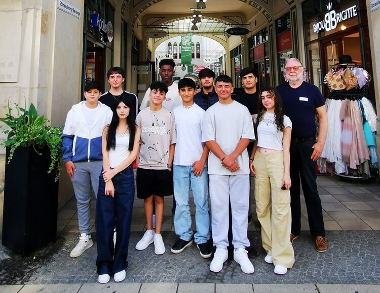 Schüler*innen aus sieben Nationen lernen gemeinsam Deutsch Schülerinnen und Schüler posieren draußen mit einer Lehrkraft für ein Gruppenfoto.