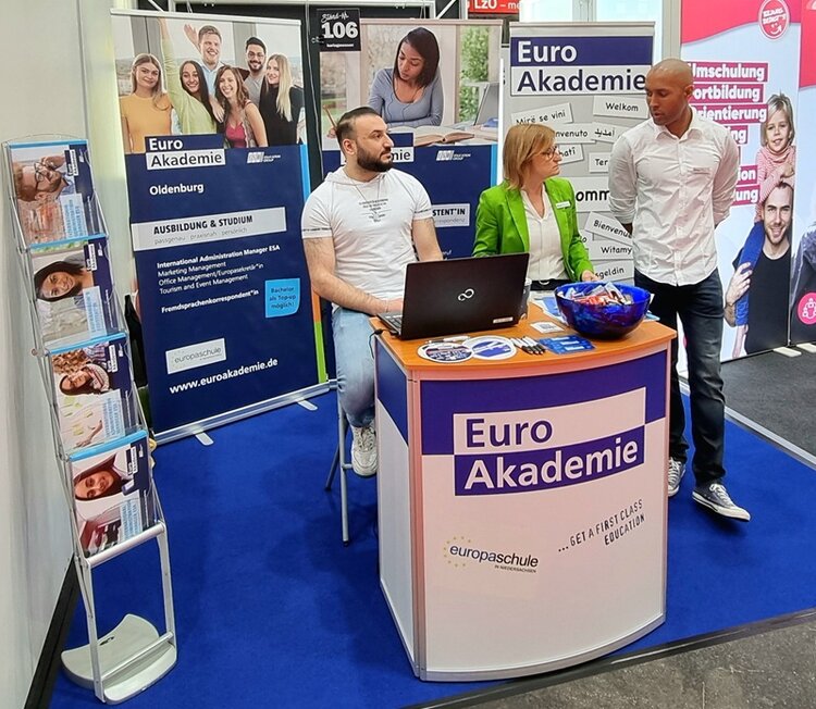 Drei Mitarbeitende der Euro Akademie und Euro-Schulen Oldenburg stehen an ihrem Messestand auf der 19. Jobmesse in Oldenburg.