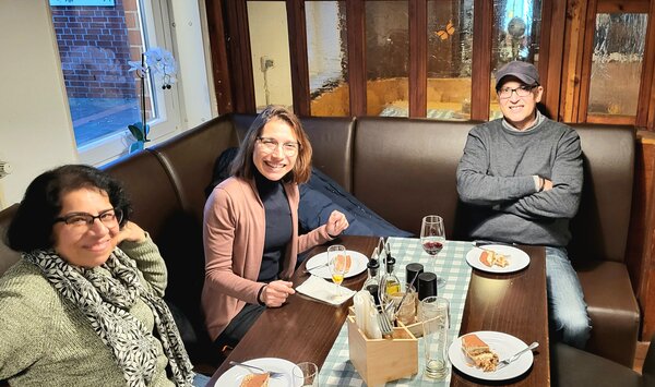 Herbstfest an der Euro Akademie und Euro-Schulen Hannover Ein männlicher und zwei weibliche Mitarbeiter*innen der Euro-Schulen bzw. Euro Akademie, die zusammen an einem Tisch in einem Restaurant sitzen und etwas essen und in die Kamera lächeln.