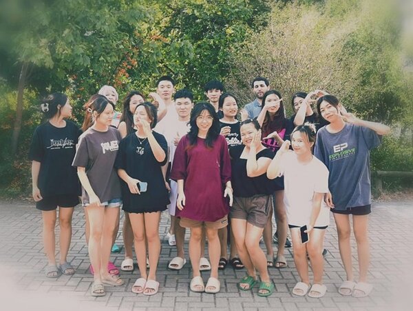 Abschluss des Deutschkurses Die Kursteilnehmenden posieren bei sommerlichem Wetter gut gelaunt mit ihrer Dozentin für ein Gruppenfoto.