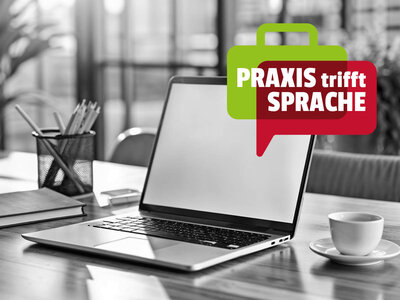 Praxis trifft Sprache - Bürokommunikation Auf dem Bild ist ein Schreibtisch in einem Büro zu sehen. Auf dem Tisch steht ein offener Laptop, daneben liegen ein Notizbuch und ein Behälter mit Stiften. Rechts vom Laptop steht eine Tasse auf einem Unterteller. Über dem Bild schwebt eine grüne Sprechblase mit dem Text "PRAXIS trifft SPRACHE" in weißer und roter Schrift. Der Hintergrund ist leicht unscharf, zeigt aber ein Büroumfeld.
