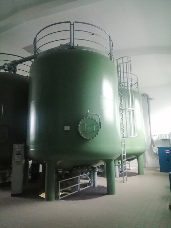 Exkursion des Berufssprachkurses B2 Aufnahme eines großen grünen Behälters, an dem eine Leiter nach oben führt, in einem Maschinenraum des Wasserwerks.