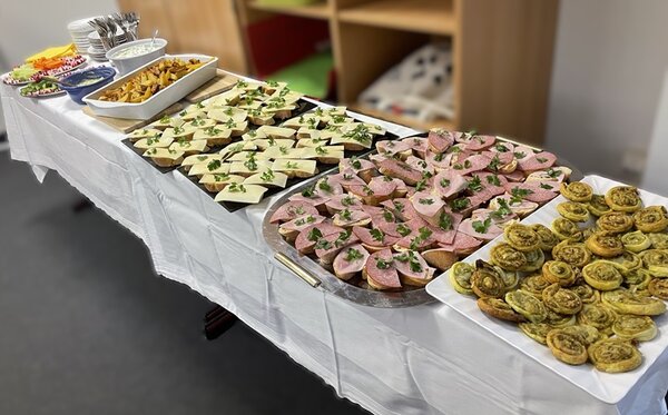 Berufsorientierung an der Euro Akademie Leipzig Langer gedeckter Buffettisch mit belegten Brötchen, Dips und Gebäck.