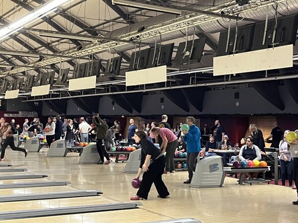 Weihnachtsfeier in Berlin Große Halle mit vielen Bowlingbahnen und den spielenden Mitarbeitenden.