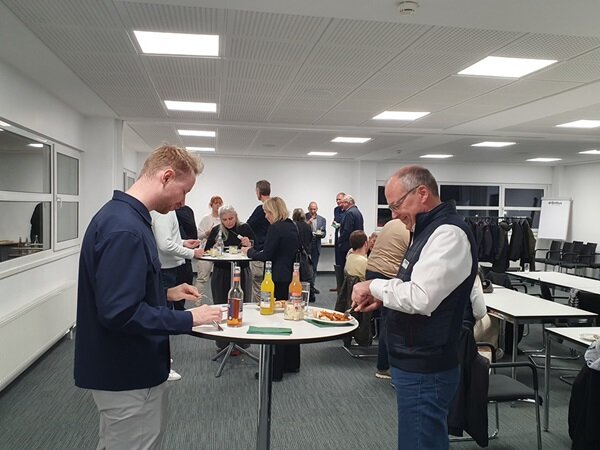 Zukunftsweisende Partnerschaften Teilnehmende stehen an Stehtischen und bedienen sich am Buffet.