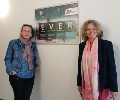 Die Teamleiterin Frau Vuksanovic-Lambert für die Agenturmaßnahme BAli und die Leiterin der Euro-Schulen Hannover Dr. Christiane Ruwoldt stehen neben einem Plakat, auf dem in großen Lettern EVER steht.