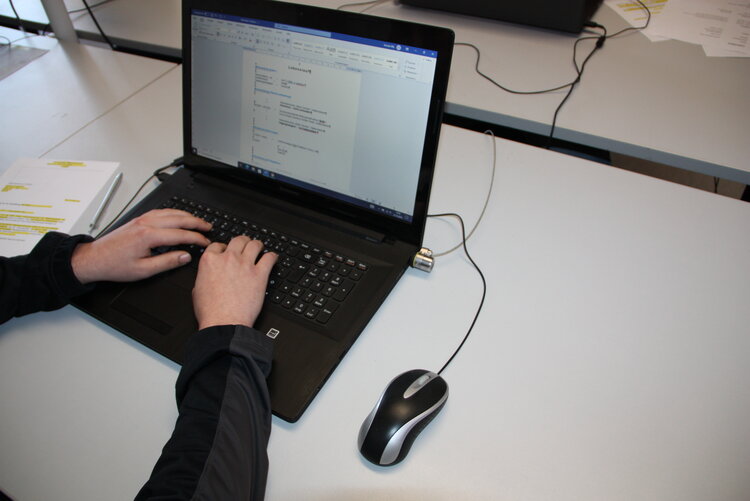 Wöchentliches Bewerbungstraining mit Jobcoach Frau Sacher Zwei Hände auf der Tastatur eines Laptops, auf dessen Monitor ein geöffnetes Dokument zu sehen ist. An den Laptop ist eine Maus angeschlossen.