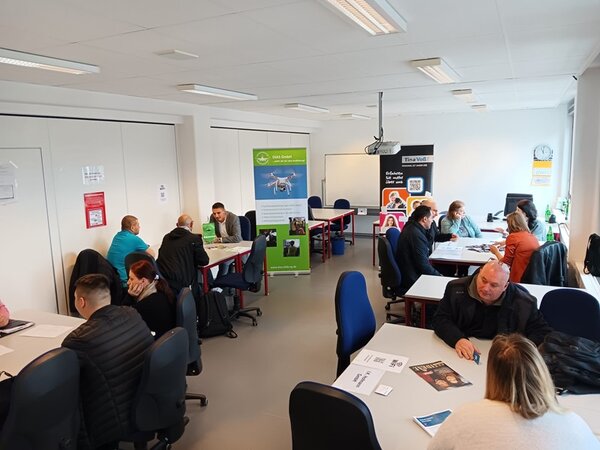 Job-Speed-Dating Teilnehmende sitzen potenziellen Arbeitgebern an Tischen gegenüber und lernen sich kennen.