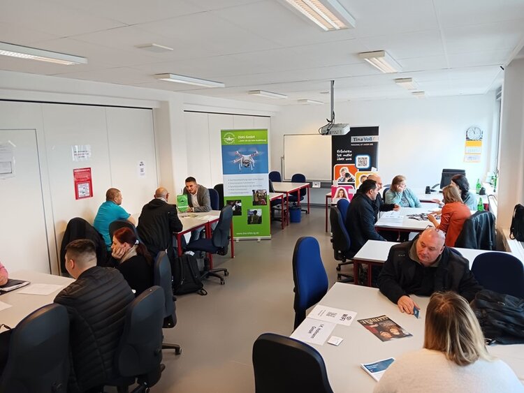 Job-Speed-Dating Teilnehmende sitzen potenziellen Arbeitgebern an Tischen gegenüber und lernen sich kennen.