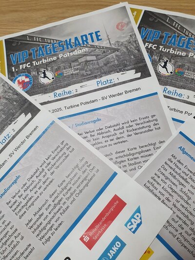 VIP-Karten 1. FFC Potsdam Auf einem Tisch liegen übereinander gefächert vier VIP Tageskarten des 1. FFC Turbine Potsdam, für das Spiel gegen SV Werder Bremen. Auf der Karte ist ein Schwarz-Weiß-Bild des Stadions abgedruckt, darunter ist der Spieltag angegeben und die Stadionregeln sind vermerkt.