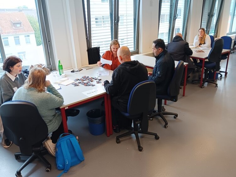 Job-Speed-Dating Teilnehmende sitzen mit Arbeitgebern an Tischen und lernen sich kennen.