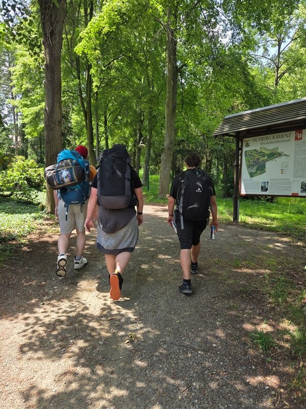 Pilgern mit Perspektive Die angehenden Fachlageristen pilgern durch den Wald und tragen alle große Rucksäcke.