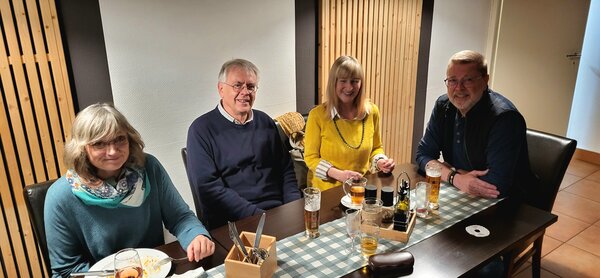 Herbstfest an der Euro Akademie und Euro-Schulen Hannover Zwei männliche und zwei weibliche Mitarbeiter*innen der Euro-Schulen bzw. Euro Akademie, die zusammen an einem Tisch in einem Restaurant sitzen und etwas essen und in die Kamera lächeln.