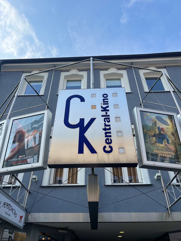 Abwechslung im Schulalltag: ein Kinobesuch Eine blaue Hauswand mit einer vorgebauten Metallkonstruktion. Daran hängt der Schriftzug des Kinos "CK Central Kino" und links und rechts davon jeweils ein Plakat von aktuellen Filmen.