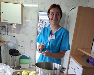 Äpfel schneiden Eine Auszubildende steht in türkiser Schütze in der Lehrküche der Euro-Schulen Hoyerswerda und schneidet die Äpfel für das Apfelmus.