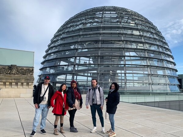 Teilnehmende posieren vor der Reichstagskuppel ein Gruppenbild.