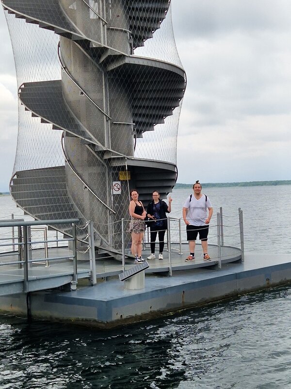 Die Auszubildenden posieren am Fuße des Pegelturm, der auf der Wasseroberfläche des Goitzschesees schwimmt für ein Gruppenbild.