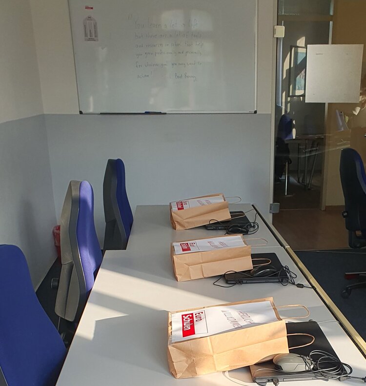 Zu sehen ist ein langer Tisch mit blauen Stühlen, auf dem Werbematerial der Euro-Schulen und Schreibwaren liegen.