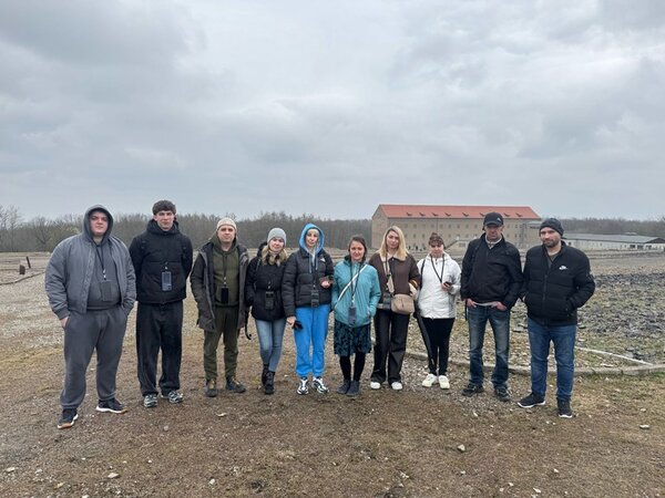 Teilnehmende stehen zusammen für ein Gruppenbild auf dem Geländer der Gedenkstätte Buchenwald in Weimar.