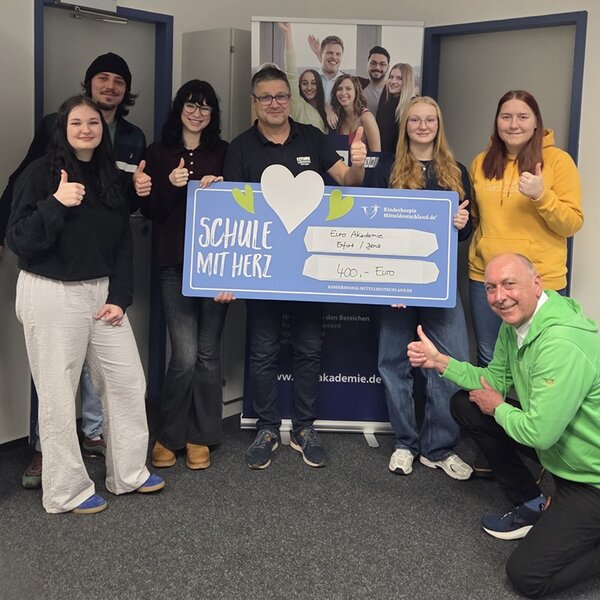 Spende an das Kinder- und Jugendhospiz Leiter Uwe Schöneck ist umringt von seinen Auszubildenden, Herr Köhler in der Hocke mit Daumen nach oben, und hält einen übergroßen Scheck über 400 Euro ins Bild.