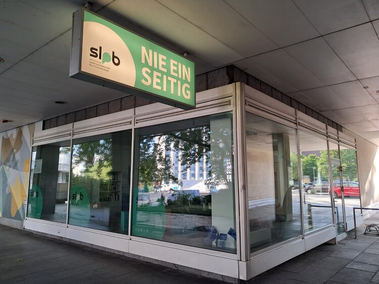 Besuch beim Projektbüro der Landeszentrale für politische Bildung Ein Schaufenster der Landeszentrale für Politische Bildung mit dem grünen Wappen lpb und Werbematerialien.