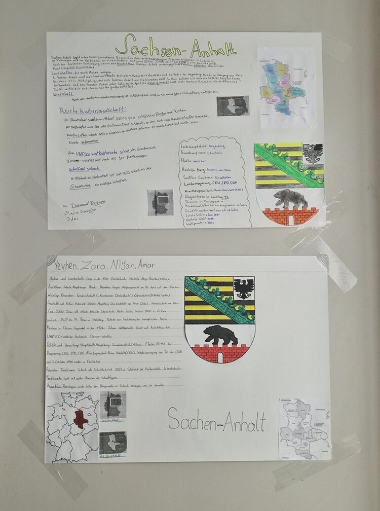 Selbst gestaltete Arbeit in Form zweier Din A4 großer Zettel mit Informationen zu Sachsen-Anhalt hängen an der Wand, mit Landeswappen und Bundesländerkarte.