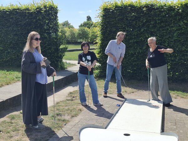 Teamtag der Euro-Schulen Berlin Brandenburg Mitarbeitende der Euro-Schulen stehen mit ihren Teams auf dem Minigolf-Platz und schauen beraten sich.