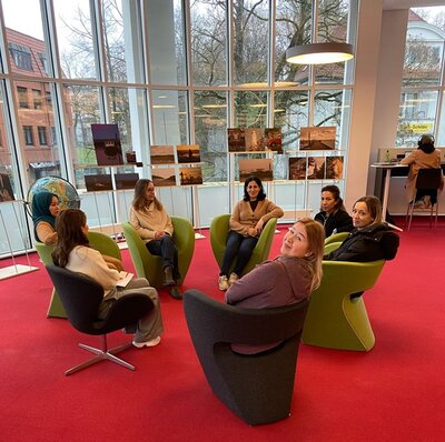 Foyer Teilnehmende sitzen im Kreis auf Sesseln im Foyer der Bibliothek.