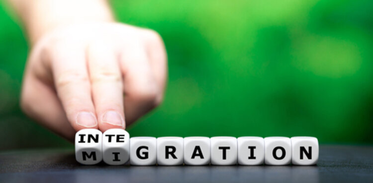 Allgemeine Integrationskurse Eine Hand dreht Würfel um und verändert damit das Wort Migration in Integration.