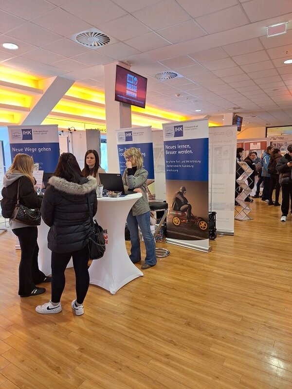 Erfolgreicher Messebesuch Zwei Teilnehmerinnen stehen am Messestand der IHK und informieren sich.