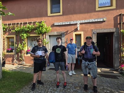 Gruppenfoto Die vier männlichen Auszubildenden zu Fachlageristen posieren nach erfolgreicher Pilgerwanderung gut gelaunt vor dem Wal- und Wüstenberghaus.