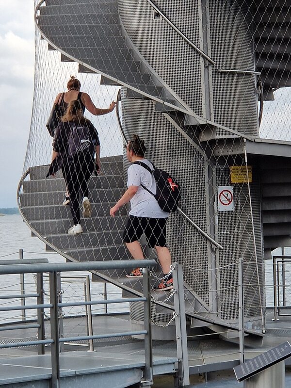 Die Auszubildenden steigen hintereinander auf den hohen Pegelturm.