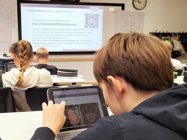 Jugendliche werden zu Faktencheckern! Auf die Wand vorne in einem Klassenzimmer wird ein Bild mit Verhaltenspunkten bei Fake News projiziert.