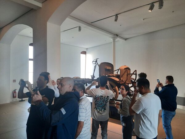 Spannende Exkursion ins Militärhistorische Museum Eine Gruppe von Menschen steht in einem Museum und betrachtet ein altes Militärfahrzeug. Einige Personen machen Fotos, während andere das Exponat betrachten.