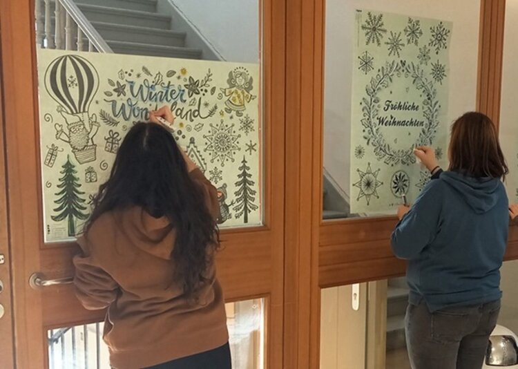 Winterliche Schultüren Zwei Schülerinnen dekorieren die Glastüren mit winterlichen Motiven.