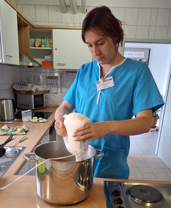 Apfelmus – Frisch vom Baum in den Topf Eine Auszubildende steht in türkiser Schütze in der Lehrküche der Euro-Schulen Hoyerswerda und püriert das zubereitete Apfelmus im Topf.