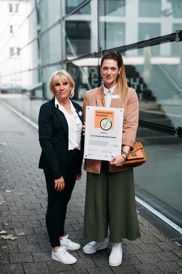 Zwei Frauen posieren mit dem Zertifikat für familienfreundliche Unternehmen.