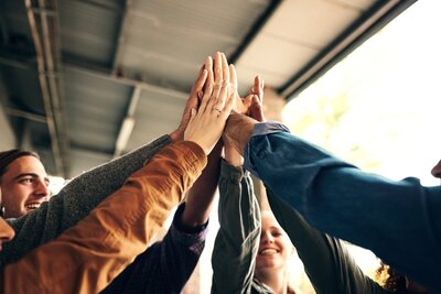 Vorbereitungskurs zum Mittleren Bildungsabschluss an den Euro-Schulen Glückliche Schülerinnen und Schüler stehen im Kreis und heben ihre Hände zum High Five. Sie freuen sich über ihren Erfolg im Vorbereitungskurs zum Mittleren Bildungsabschluss an den Euro-Schulen Wiesbaden.