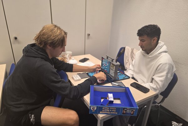 Spielen, Sprechen, Spaß haben – Kreative Gesprächsanlässe im Jugendintegrationskurs Zwei junge Männer spielen Schiffe versenken an einem Tisch. Einer setzt gerade Schiffe auf dem Spielfeld, während der andere konzentriert zuschaut.